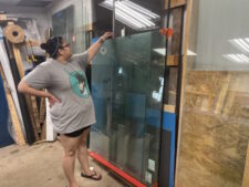 Beverly Hills Janay at glass rack, pointing to a large sheet leaning against the wall