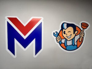 Vectra logo (stylized letter M in red and blue with white outline(, and Flow-Rite logo (cartoon plumber winking, and wielding a wrench and plunger).